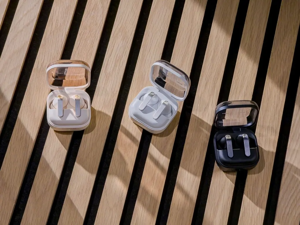علب شحن سماعات Galaxy Buds4 الشفافة على طاولة خشبية