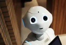 روبوت أبيض صغير بعينين مضيئتين قرب حاسوب