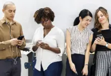 أربعة شباب ينظرون إلى هواتفهم أمام جدار أبيض