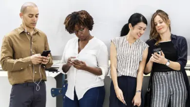 أربعة شباب ينظرون إلى هواتفهم أمام جدار أبيض