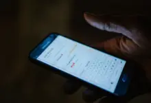 يد تمسك هاتفًا في الظلام تظهر على شاشته لوحة مفاتيح ورسالة