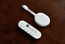 جهاز Chromecast with Google TV الأبيض مع ريموته على طاولة خشبية