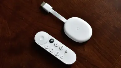 جهاز Chromecast with Google TV الأبيض مع ريموته على طاولة خشبية