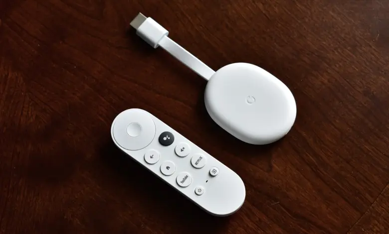 جهاز Chromecast with Google TV الأبيض مع ريموته على طاولة خشبية