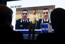 شاشة في مؤتمر تعرض صورة مع عبارة حقيقي أم مزيّف حول التزييف العميق