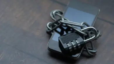 هاتف ملفوف بسلسلة معدنية وقفل برقم سري على طاولة خشبية