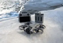 طائرة DJI Avata 360 مع جهاز التحكم والبطاريات على صخرة بجانب البحر