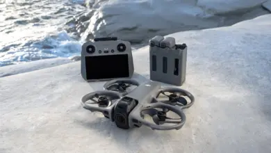 طائرة DJI Avata 360 مع جهاز التحكم والبطاريات على صخرة بجانب البحر