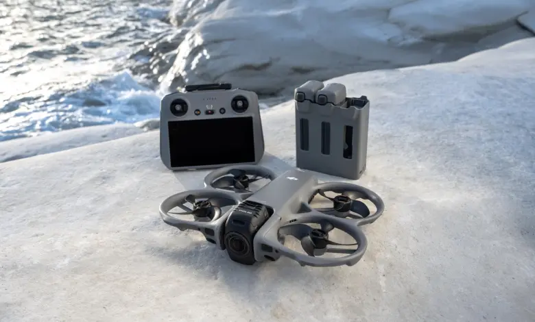 طائرة DJI Avata 360 مع جهاز التحكم والبطاريات على صخرة بجانب البحر