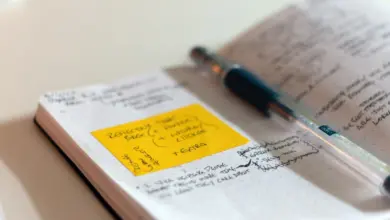 دفتر ملاحظات مفتوح عليه بطاقة صفراء وقلم