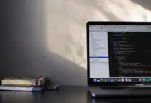 حاسوب محمول على مكتب مع كتب وشاشة تعرض بيئة عمل