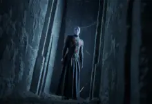 Pinhead واقفًا في ممر حجري مظلم في لعبة Hellraiser Revival