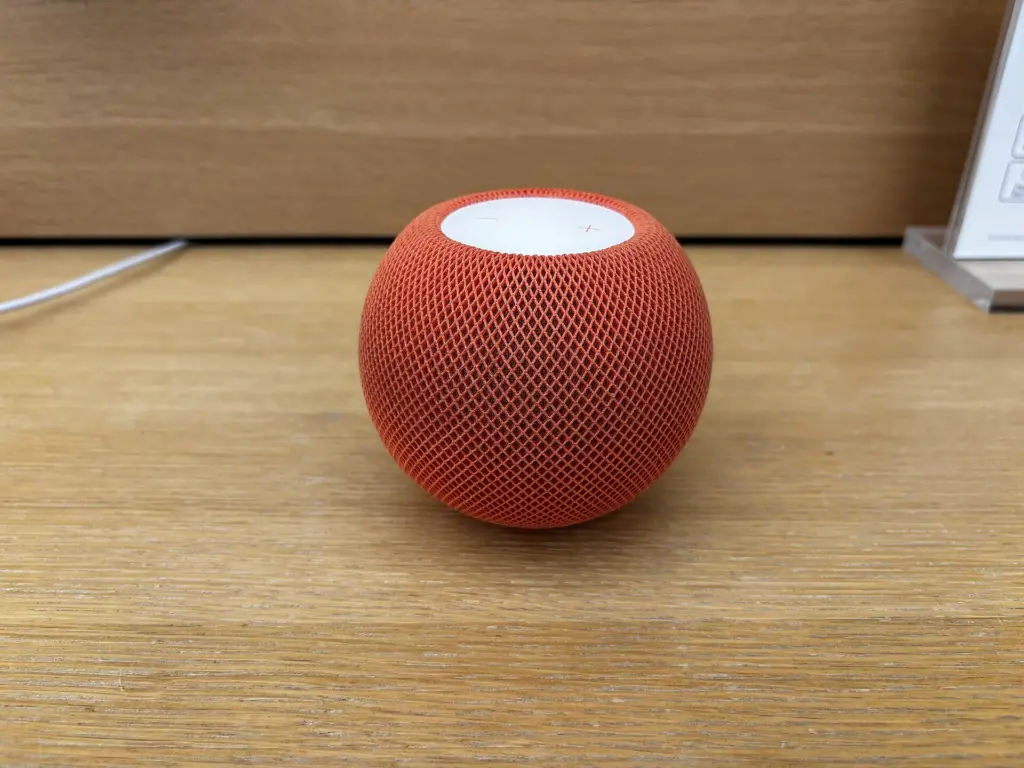 سماعة HomePod mini برتقالية على رف خشبي