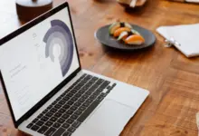 حاسوب محمول يعرض مخططًا دائريًا على مكتب خشبي