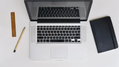 لابتوب ماك على مكتب بجانب دفتر وقلم