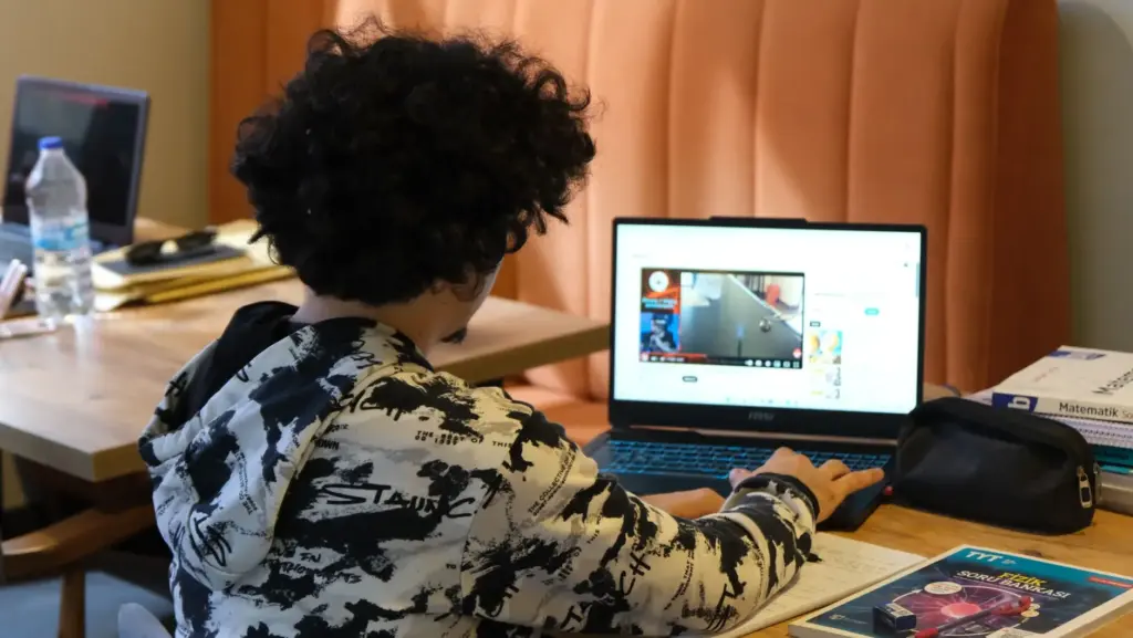 ولي أمر يساعد طفله في الواجب المدرسي أمام حاسوب محمول