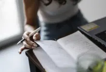 شخص يكتب في دفتر ملاحظات على مكتب