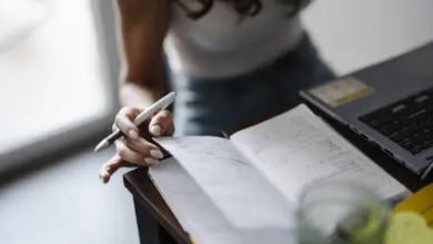 شخص يكتب في دفتر ملاحظات على مكتب