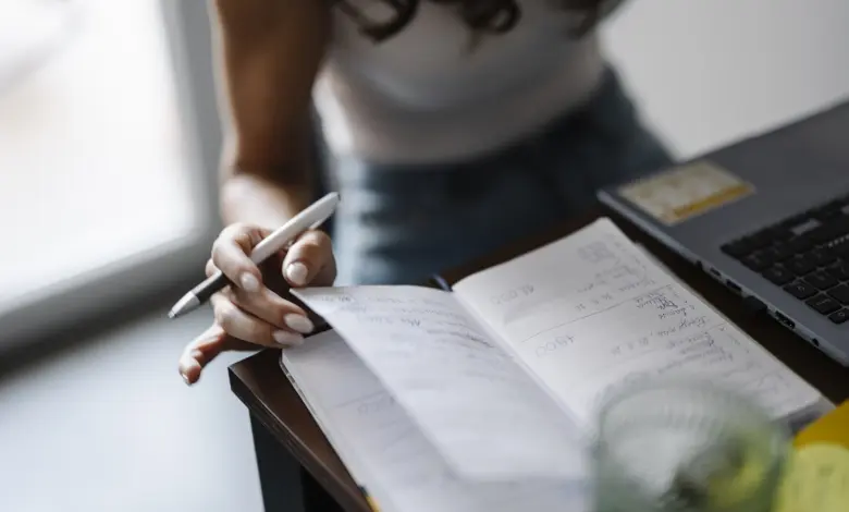شخص يكتب في دفتر ملاحظات على مكتب