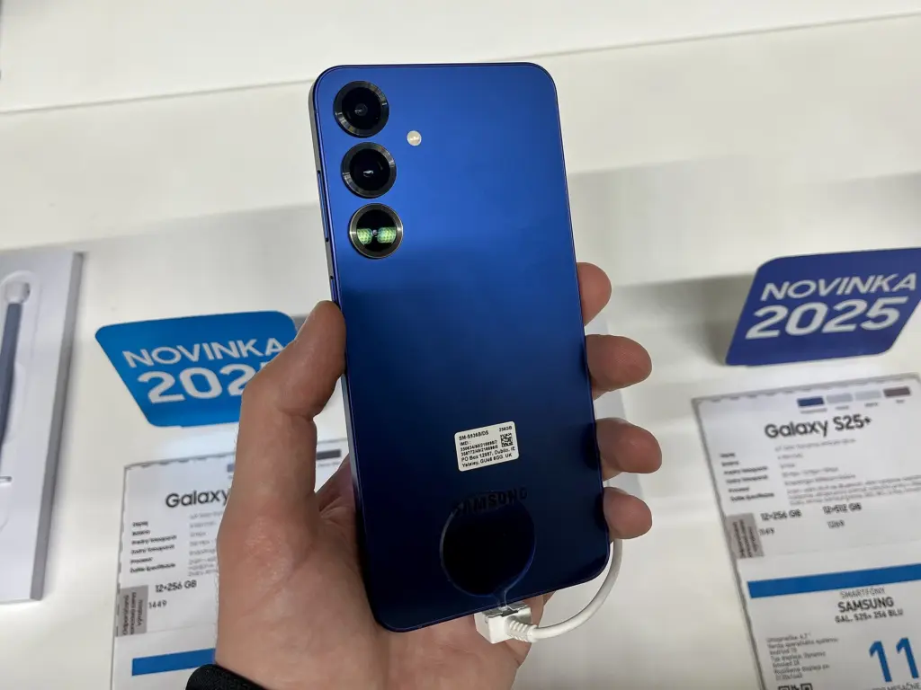 هاتف Samsung Galaxy S25+ أزرق من الخلف في يد زائر بمعرض بيع