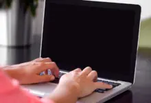 يدان على لوحة مفاتيح لابتوب أثناء الكتابة