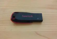 فلاشة USB سوداء من SanDisk موضوعة على سطح خشبي