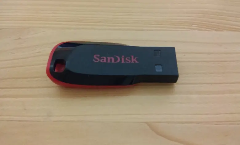 فلاشة USB سوداء من SanDisk موضوعة على سطح خشبي