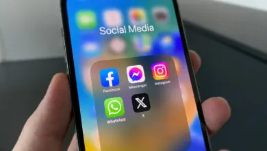 يد تمسك هاتفًا تظهر عليه أيقونات تطبيقات التواصل الاجتماعي ومنها Instagram