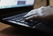 يد على لوحة مفاتيح لابتوب أسود