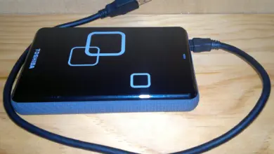 قرص خارجي أسود متصل بكابل USB على سطح خشبي