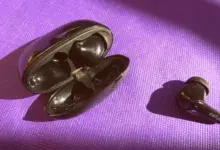 سماعة لاسلكية سوداء وعلبة الشحن على خلفية بنفسجية