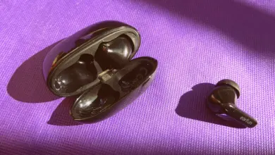 سماعة لاسلكية سوداء وعلبة الشحن على خلفية بنفسجية
